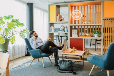 Homme d’affaires en communication dans un espace convivial de l’Appart’hôtel Appart’City Paris Roissy CDG, avec un décor moderne et confortable