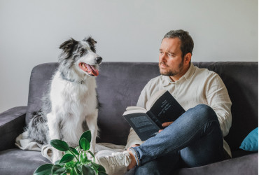 Moment détente dans l’Appart’hôtel Appart’City Montpellier, avec un homme lisant sur un canapé en compagnie d’un chien, dans un espace chaleureux et moderne