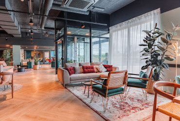 Lobby élégant et chaleureux de l’Appart’hôtel Appart’City Paris Roissy CDG, avec une décoration moderne, des fauteuils en velours vert, un canapé confortable et des plantes apportant une touche naturelle