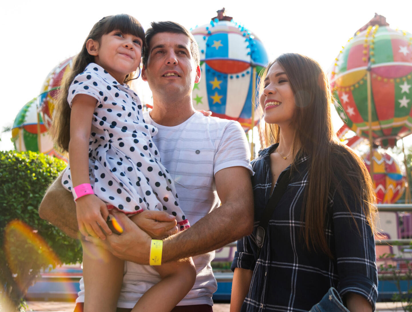Famille heureuse au Parc du Petit Prince avec manèges colorés en arrière-plan