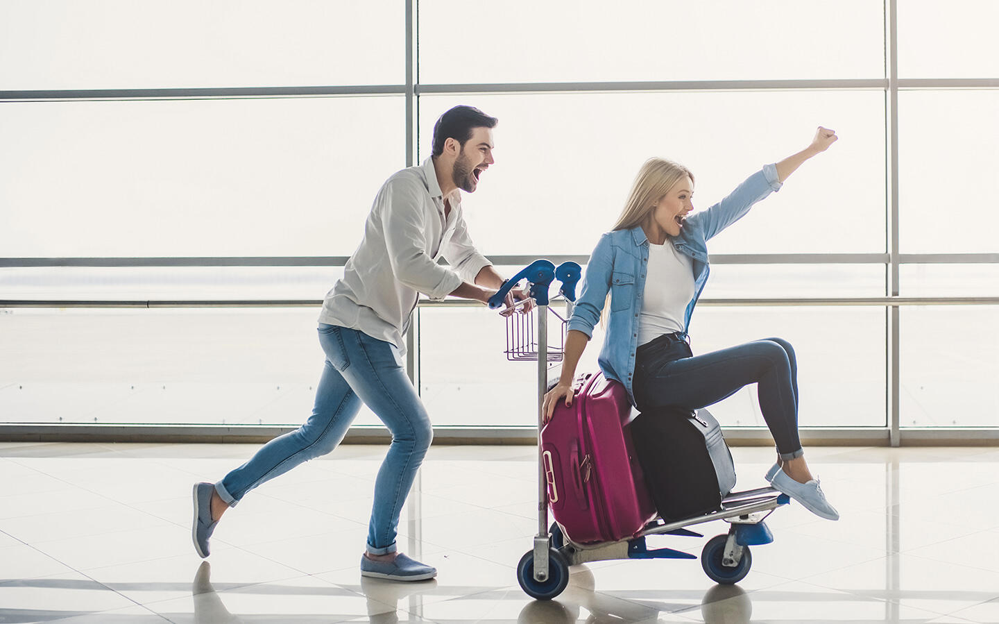 Una pareja feliz en el aeropuerto de Orly, el hombre empujando a la mujer en un carrito de equipaje