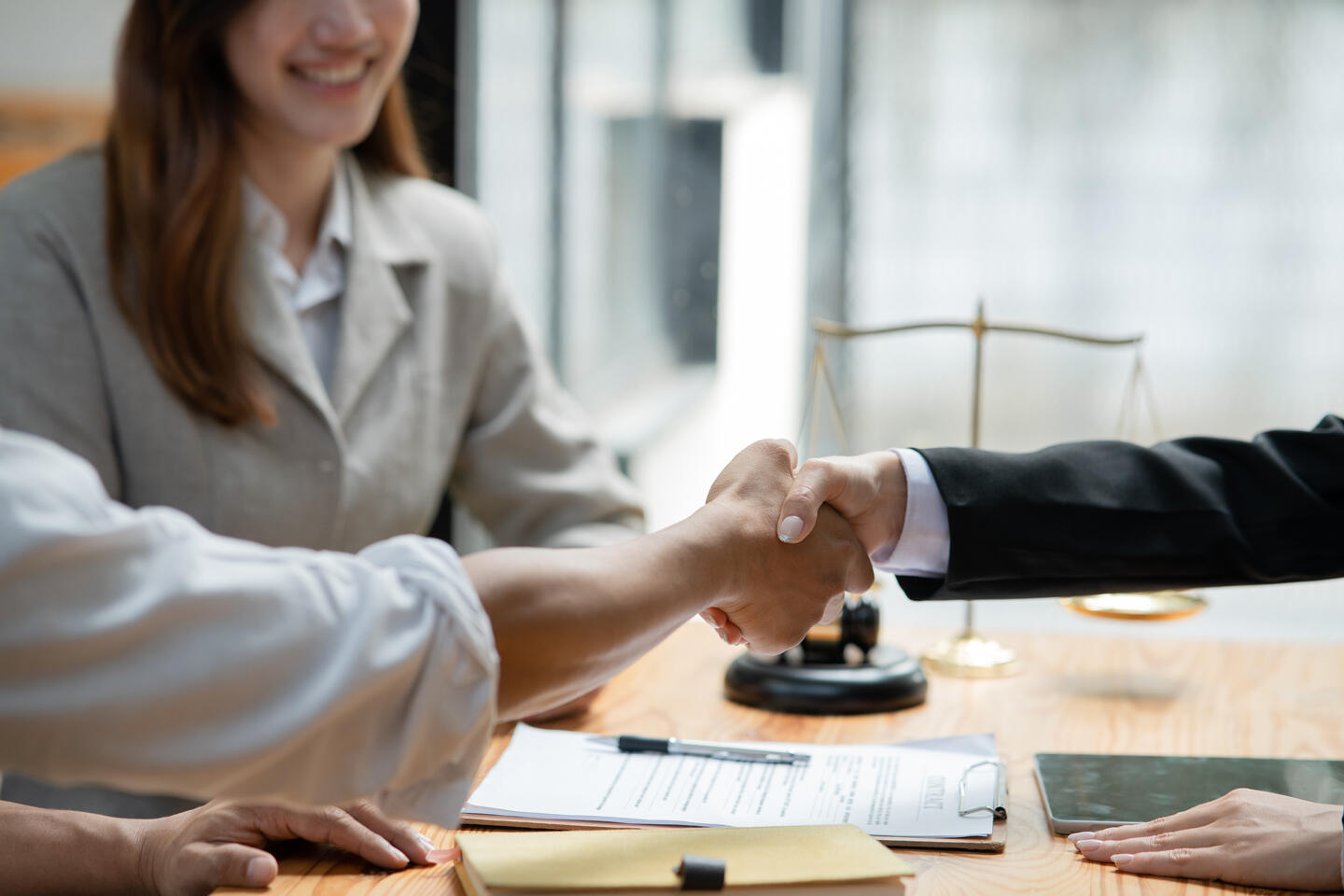 Handshake between two people in the presence of a mediator, representing an agreement or conflict resolution for Appart'CIty mediation page.