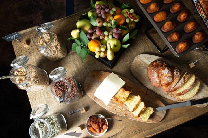 Gourmet-Frühstück in einem Aparthotel der Collection-Kollektion mit frischem Obst, handwerklichem Brot, Gebäck, Müsli und Trockenfrüchten.