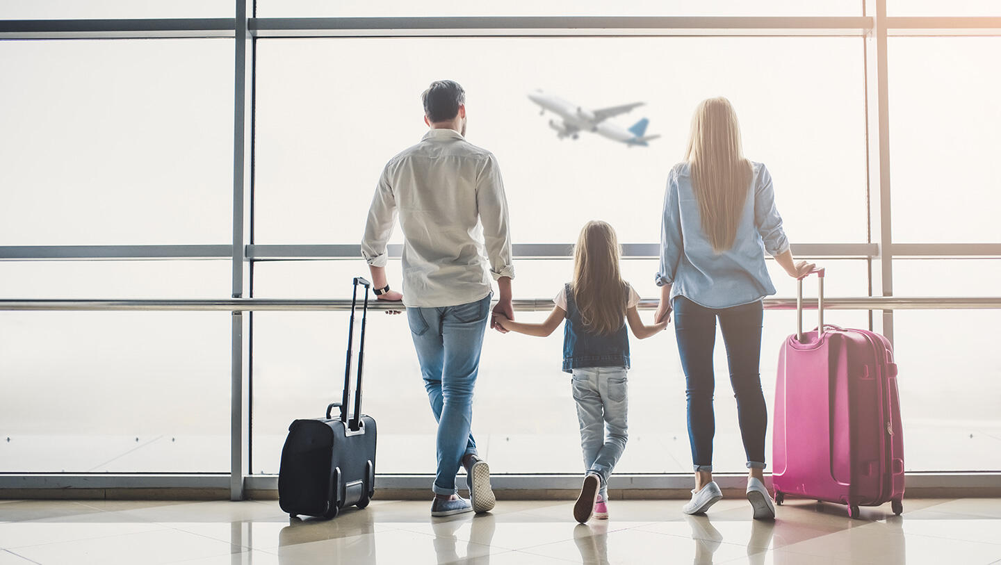 Famille regardant un avion décoller à l'aéroport le Bourget, tenant les mains et avec des bagages