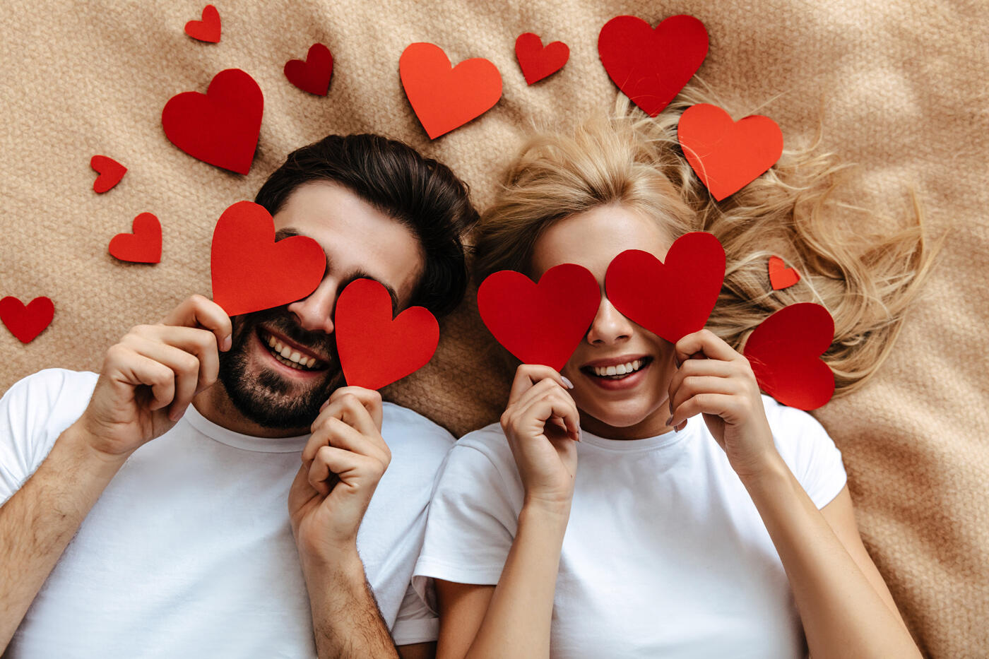 Couple joyeux célébrant la Saint-Valentin avec des cœurs rouges, idéal pour une offre restaurant et nuitée romantique à l'appart'hôtel Appart'City Roissy CDG.